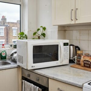an LG microwave oven on a worn laminate kitchen worktop in a lived-in upper-floor flat in Islington, North London